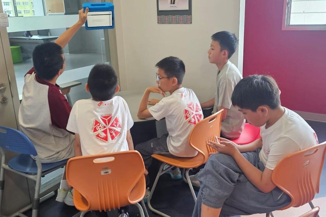 A group of kids at Einstein International sitting together, attentively checking on something in a calm and focused setting.